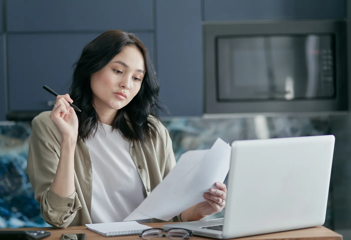 Woman reviewing eligibility documents beside a laptop at home