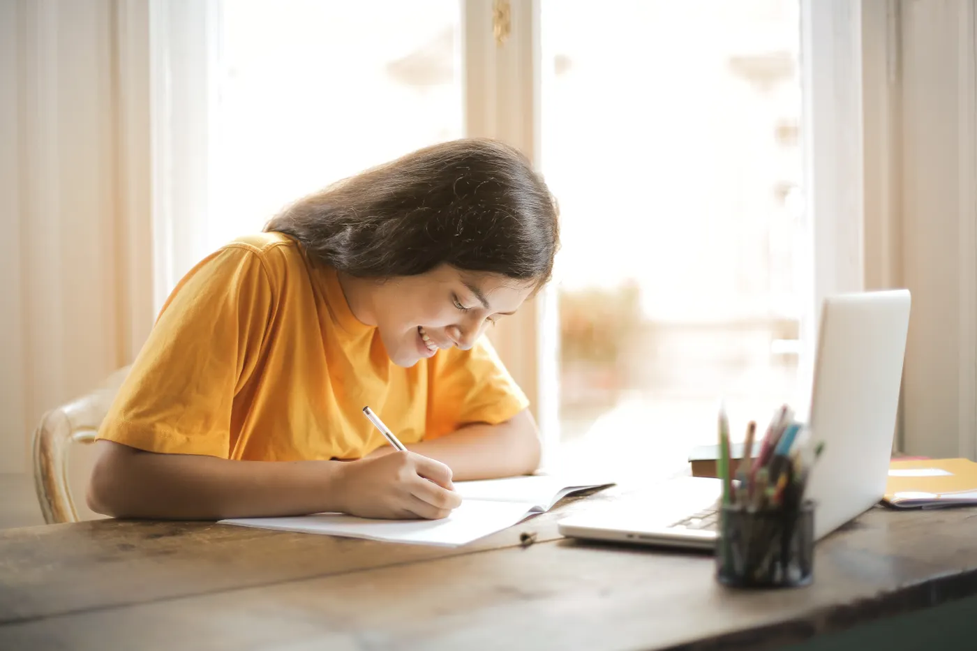 Adult learner studying online with a laptop and notebook at home