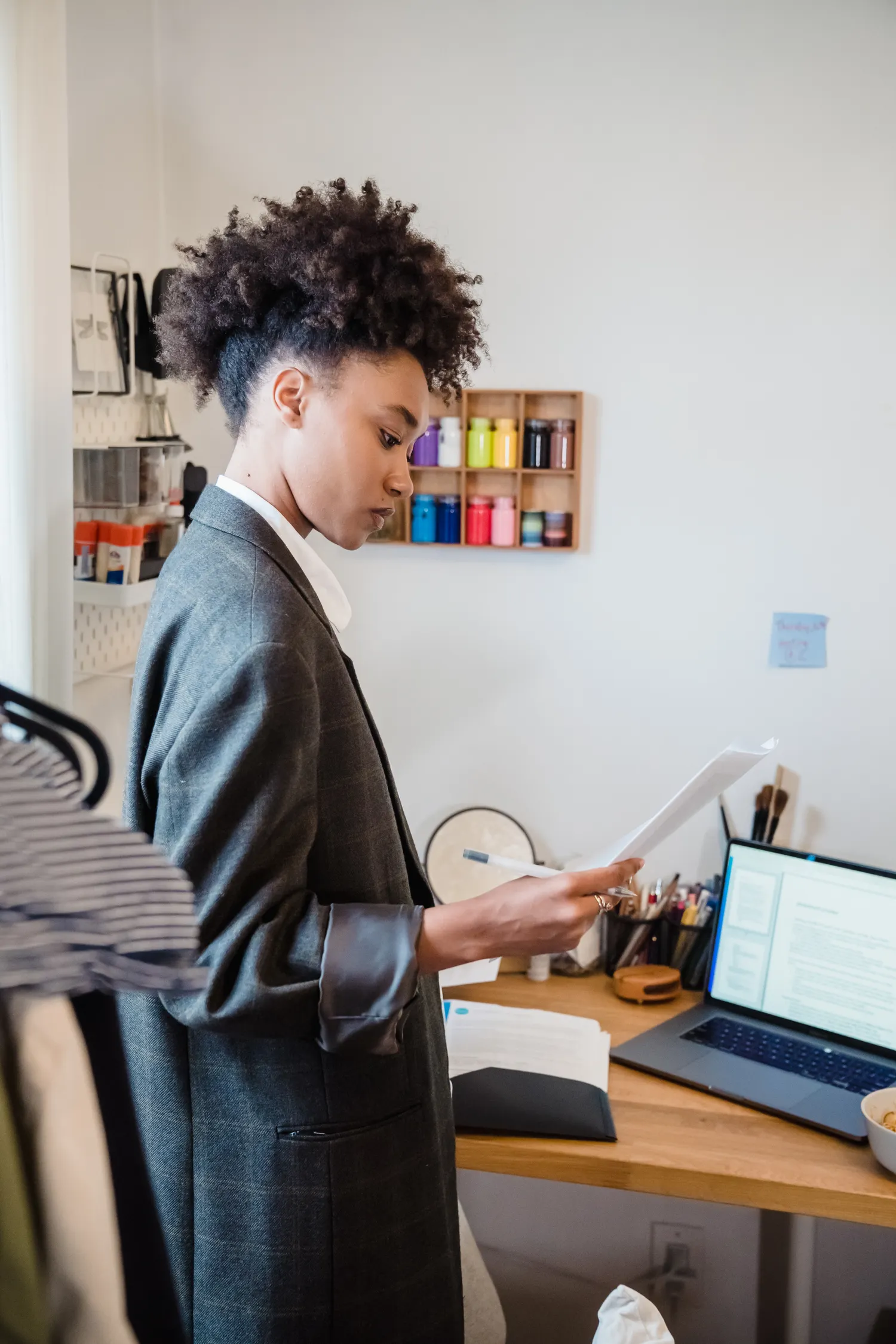 Adult reviewing laptop assistance paperwork beside a laptop at home