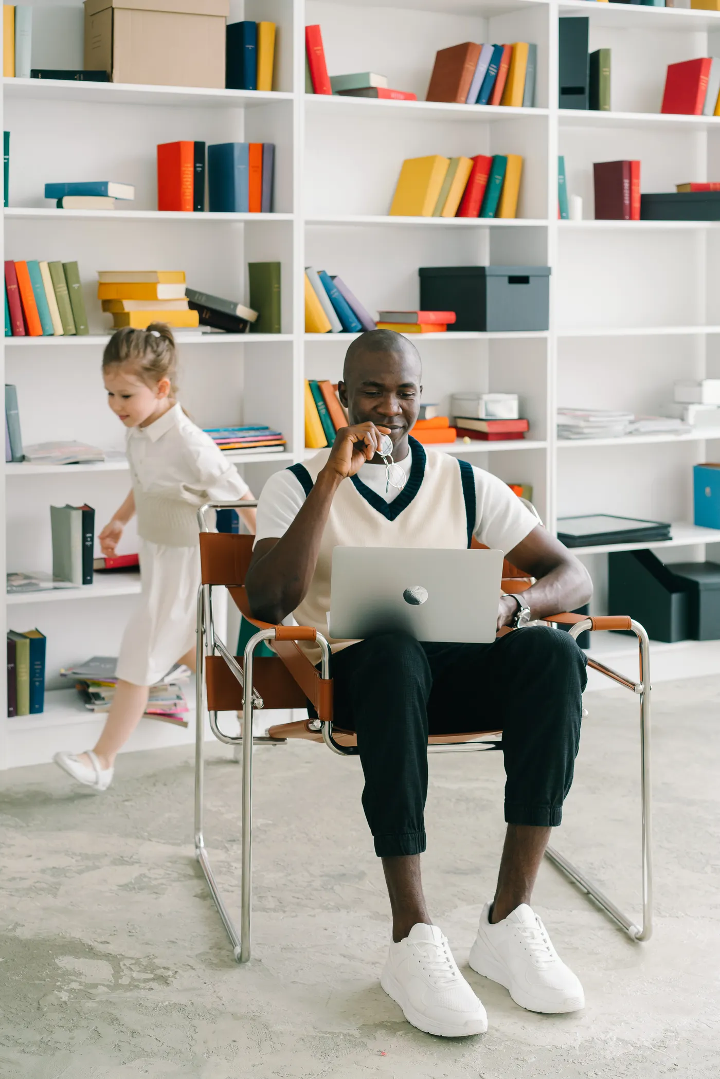 Adult using a laptop in a library with a child nearby