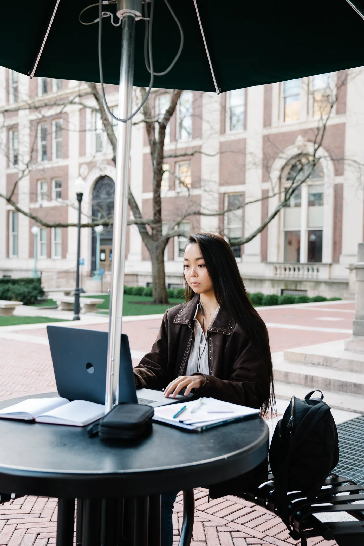 College student using a laptop with study materials on campus